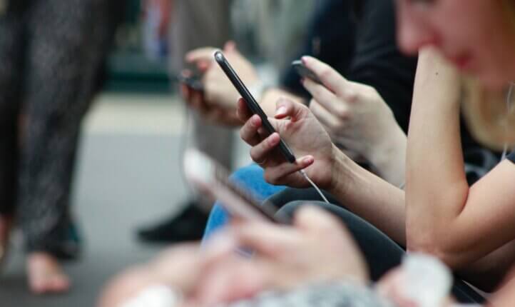 People sitting on a bench browsing their phones