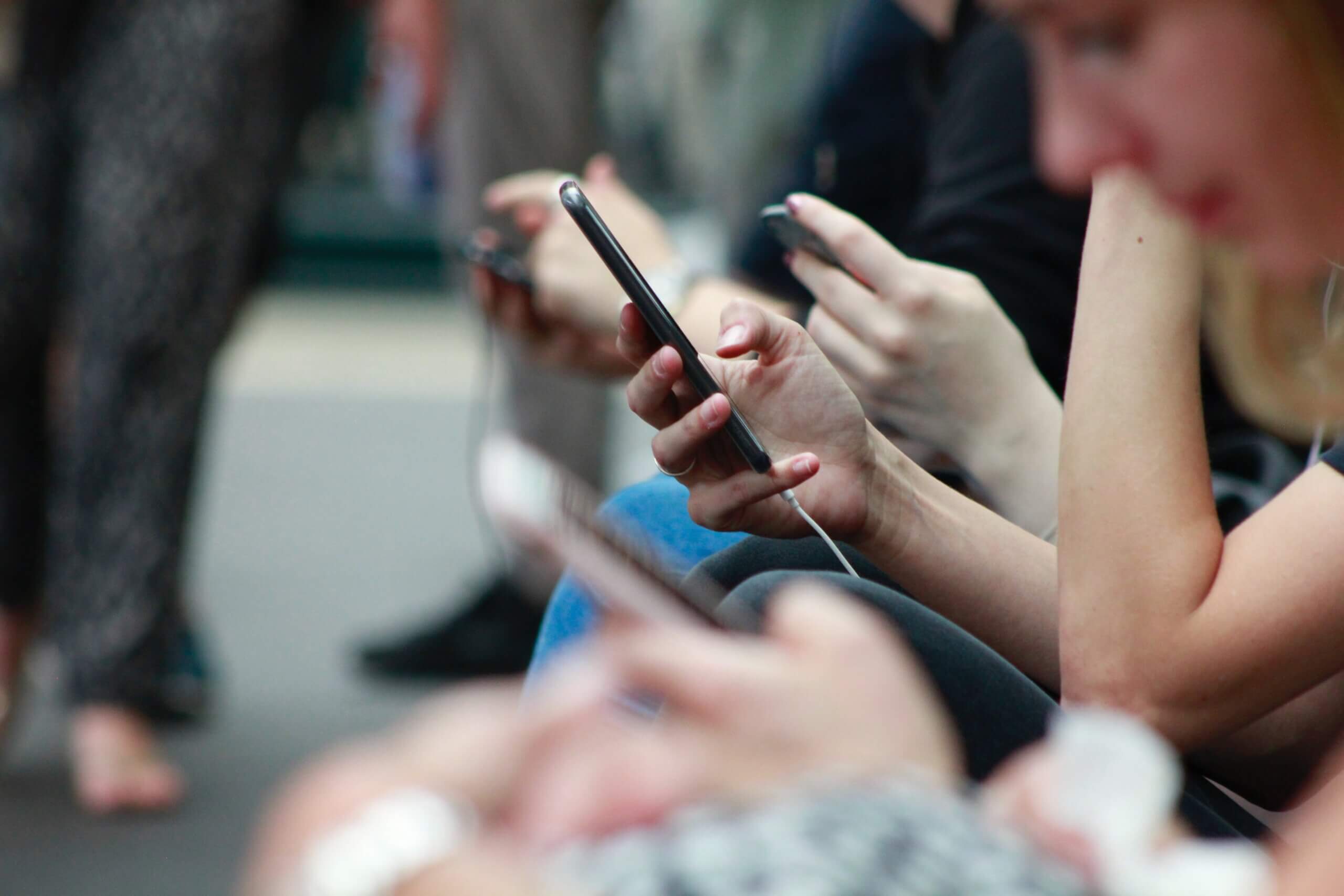 People sitting on a bench browsing their phones