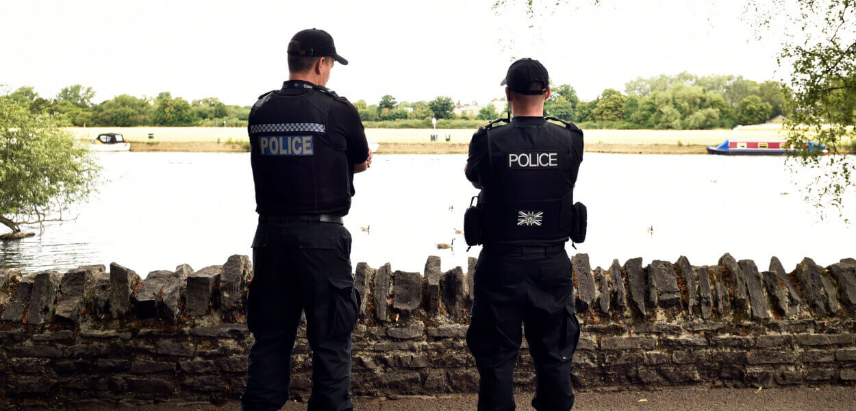 Police officers with caps on near river