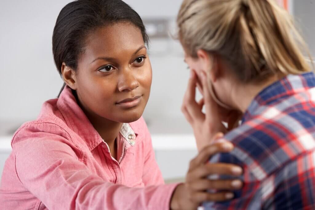 Woman being comforted by professional with her hand on her shoulder