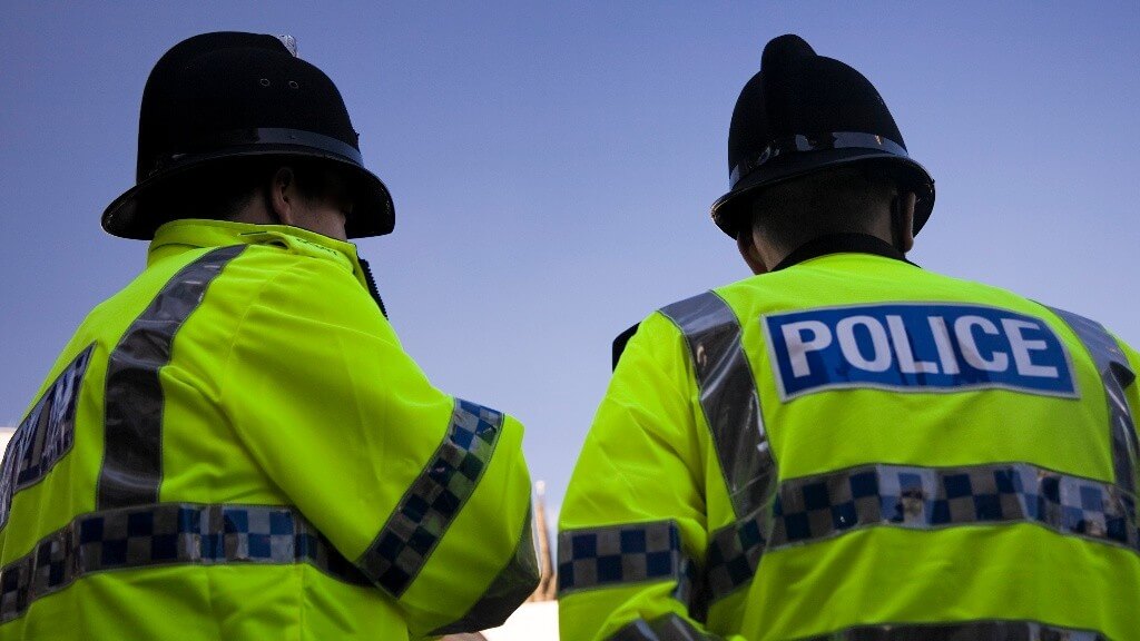 The backs of two neighbourhood police officers wearing custodian helmets