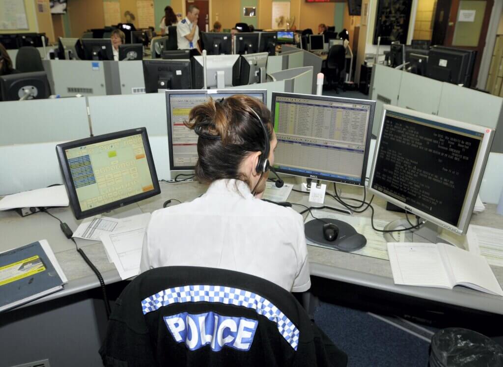 Contact Management Centre. Member of Police staff taking a call with computer screens in front of her