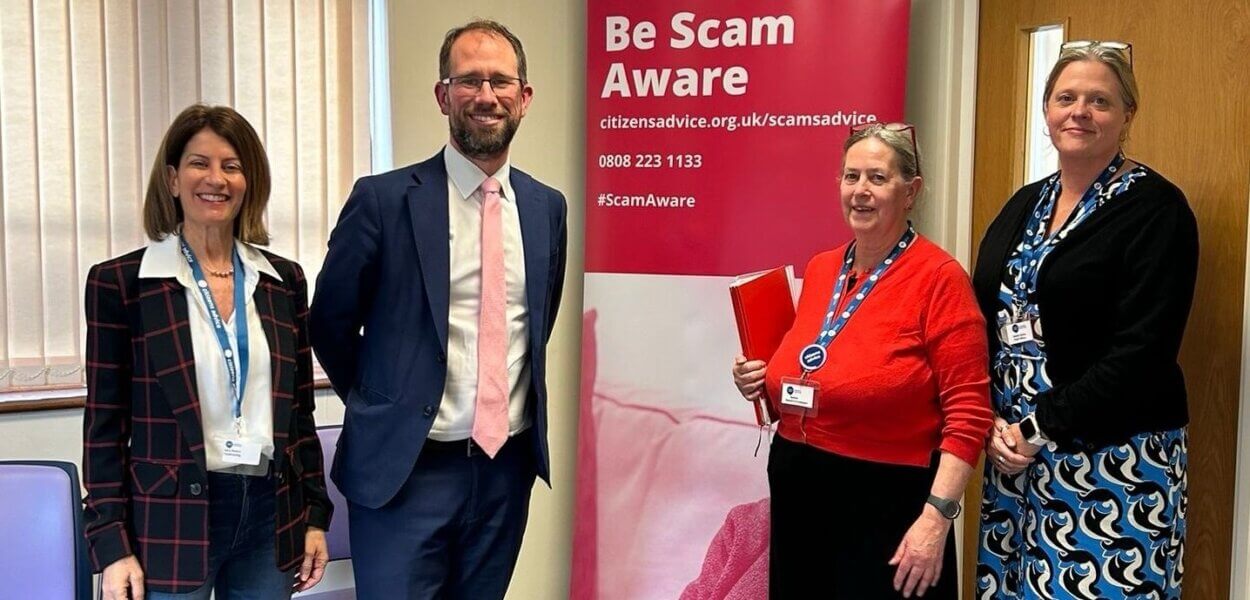 Matthew Barber with representatives from Citizens Advice Oxfordshire South & Vale in front of a Be Scam Aware banner