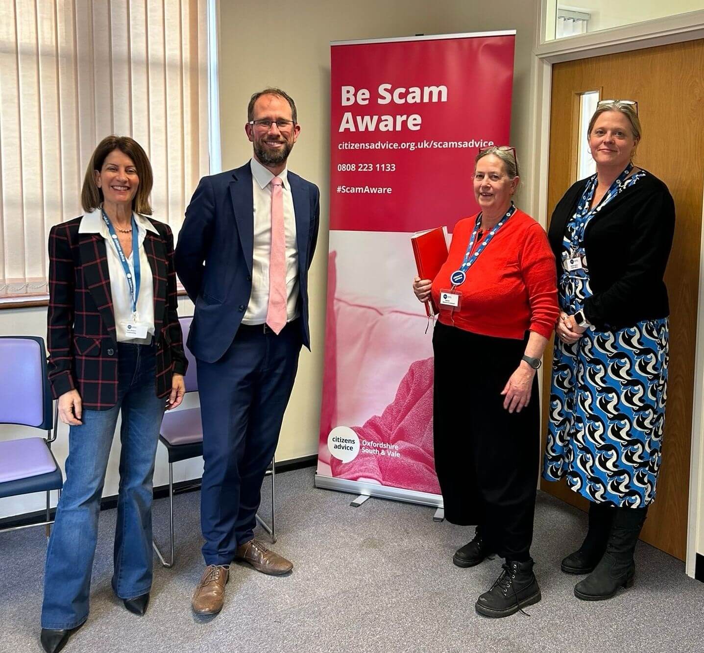 Matthew Barber with representatives from Citizens Advice Oxfordshire South & Vale in front of a Be Scam Aware banner