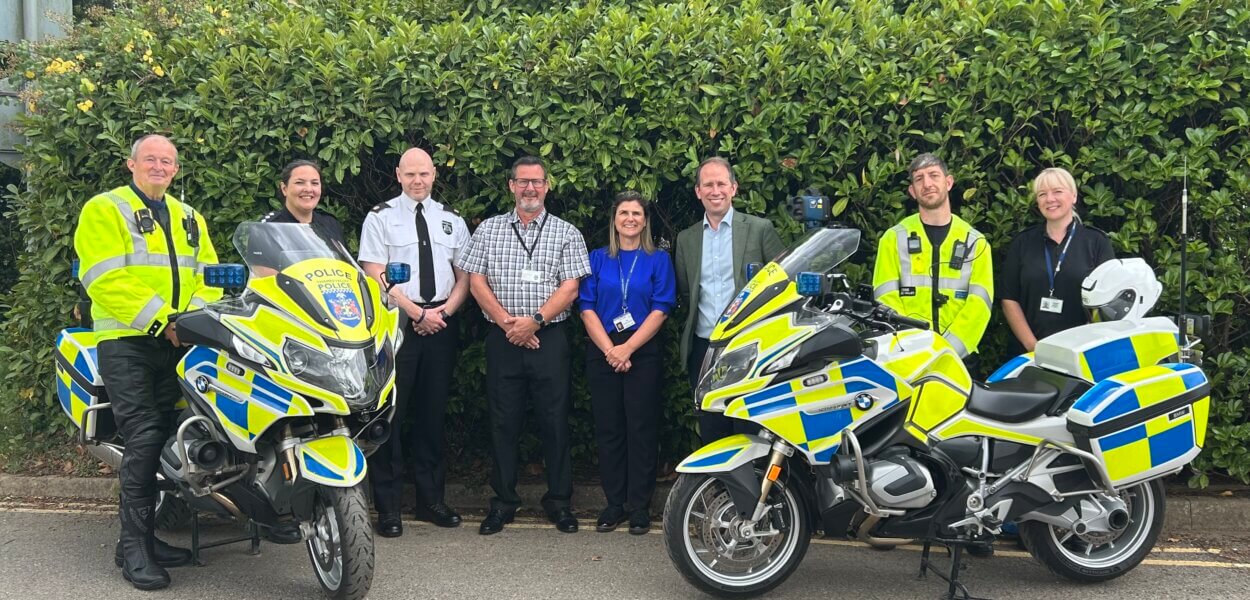 Thames Valley Police and Crime Commissioner, Matthew Barber, with officers and staff from TVP's Roads Policing Unit. The group of 8 are standing behind two of the enforcement motorbikes.