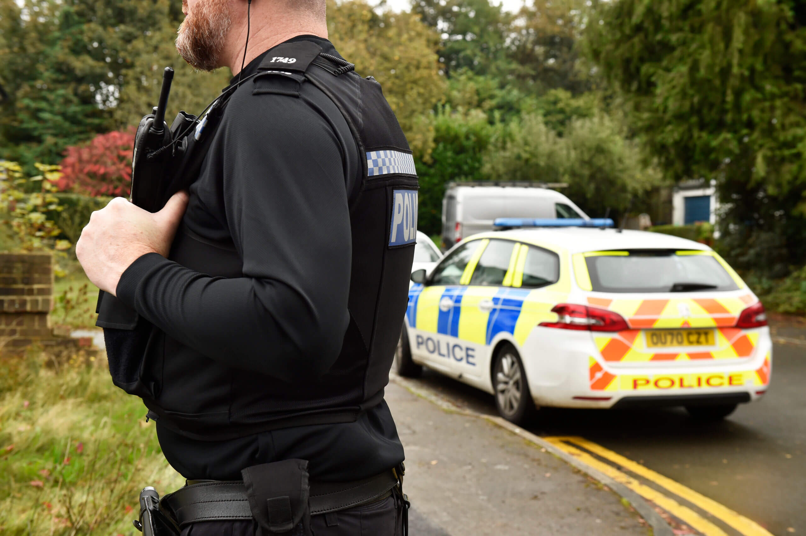A Thames Valley police officer by a police vehicle in a village.